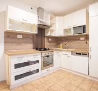 Slnečný 3-izbový byt, Kramáre - Kuchyňa v 3-izbovom byte s bielymi skrinkami a podlahou s dreveným dekorom.