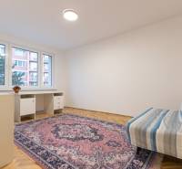 Slnečný 3-izbový byt, Kramáre - Izba s podlahou s dreveným dekorom, kobercom, stolíkom a pohovkou v 3-izbovom byte.