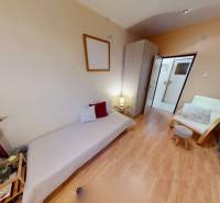 NAJLACNEJŠÍ 3- izbový byt v Topoľčanoch, neďaleko ZKW - Izba s posteľou, kreslom a podlahou s dreveným dekorom v 3-izbovom byte.