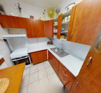 NAJLACNEJŠÍ 3- izbový byt v Topoľčanoch, neďaleko ZKW - Kuchyňa v 3-izbovom byte, s dreveným dekorom, skrinky a biela pracovná doska.