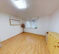 NAJLACNEJŠÍ 3- izbový byt v Topoľčanoch, neďaleko ZKW - Izba v 3-izbovom byte s podlahou s dreveným dekorom a jednoduchým nábytkom.