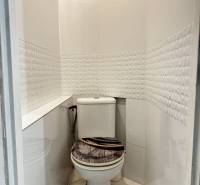 3 izbový byt s dvoma pivnicami Topoľčany - Kúpeľňa so záchodom v 3-izbovom byte, obklad s geometrickým vzorom a podlaha s dreveným dekorom.