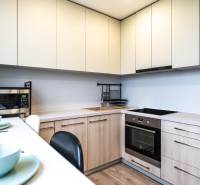 Útulný 2-izbový byt na prenájom - Kuchyňa v 2-izbovom byte s bielymi skrinkami, mikrovlnkou a varnou doskou.