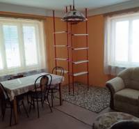 Na predaj rodinný dom Kosihovce - Obývacia izba v rodinnom dome s jedálenským stolom a policovým rebríkom.