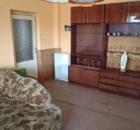 Na predaj rodinný dom Kosihovce - Obývačka v rodinnom dome s pohovkou a vitrínou s pohármi.