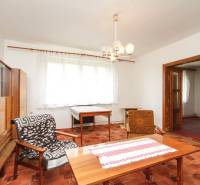 Dom s veľkým pozemkom 3099m2, Melčice-Lieskové - Obývacia izba rodinného domu s retro nábytkom a vzorovaným kobercom, osvetlená lusterom.