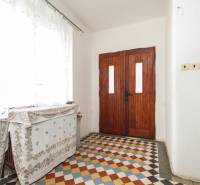 Dom s veľkým pozemkom 3099m2, Melčice-Lieskové - Drevené dvere v chodbe rodinného domu s farebnou dlažbou a minimalistickým dekorom.