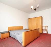 Dom s veľkým pozemkom 3099m2, Melčice-Lieskové - Spálňa so starším nábytkom, červený koberec a jednoduché svietidlo v rodinnom dome.