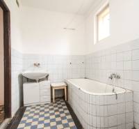 Dom s veľkým pozemkom 3099m2, Melčice-Lieskové - Kúpeľňa s vaňou v rodinnom dome, biele obklady, šachovnicová podlaha, prirodzené svetlo.
