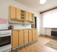 Dom s veľkým pozemkom 3099m2, Melčice-Lieskové - Kuchyňa so starším nábytkom, sporákom a veľkým oknom, súčasť rodinného domu.