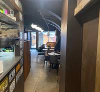 Reštaurácia na predaj v centre Košíc na Hlavnej 74 - Interiér gastro priestorov s taniermi na polici, tabule, stoly a stoličky.