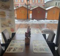 Reštaurácia na predaj v centre Košíc na Hlavnej 74 - Zimná scenéria cez okno gastro priestoru s pohľadom na drevené stolíky.