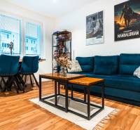 Na prenájom moderný 2-izbový byt  - Obývačka v 2-izbovom byte s modrou sedačkou a podlahou s dreveným dekorom.