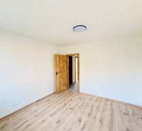 REZERVOVANÉ  Investičná trefa: 3i byt za dočasne zníženú cenu - Miestnosť v 3-izbovom byte s bielymi stenami a podlahou s dreveným dekorom.
