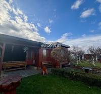 Predaj, záhradný pozemok   231 m2 Spišská Nová Ves, ... - Drevená chatka v záhradách Spišskej Novej Vsi s lavičkami a kvetinovým záhonom.
