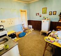 Na predaj 4-izbový rodinný dom v Brodzanoch – pozemok 1236 m² - Kuchyňa v rodinnom dome s jedálenským stolom, starším sporákom a chladničkou.