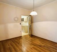 Výborná poloha, skvelá dispozícia – 3-izbový byt v Trebišove - Izba v 3-izbovom byte s podlahou s dreveným dekorom, pohľad do kuchyne.