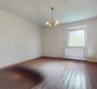 Veľký priestranný pozemok o rozlohe 7445 m2, Jelka  - Prázdna izba s drevenou podlahou a lustrom v rodinnom dome.