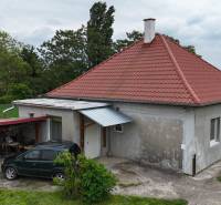 Veľký priestranný pozemok o rozlohe 7445 m2, Jelka  - Rodinný dom na ulici Slaná dolina v Jelke s červenou strechou a prístreškom auta.