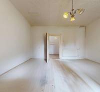 Veľký priestranný pozemok o rozlohe 7445 m2, Jelka  - Priestranná miestnosť s bielou podlahou, radiátorom a lustrom v rodinnom dome.