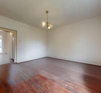 Veľký priestranný pozemok o rozlohe 7445 m2, Jelka  - Prázdna izba s drevenou podlahou a lustrami v rodinnom dome.