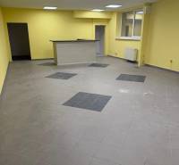 PRENÁJOM OBCHODNÉHO priestoru , NITRA - Štúrova ulica - Žlté steny, šedá podlaha a drevený pult v obchodných priestoroch.