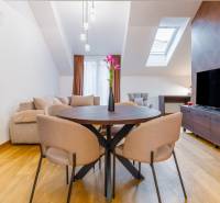 NOVOSTAVBA | 2i Mezonet + 1i štúdio s terasou a parkingom v CENTRE PO - Interiér 1-izbového bytu so stolom, sedačkou a podlahou s dreveným dekorom.