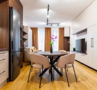 NOVOSTAVBA | 2i Mezonet + 1i štúdio s terasou a parkingom v CENTRE PO - Interiér 1-izbového bytu s podlahou s dreveným dekorom, kuchyňou a jedálenským stolom.