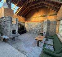 Skrytý raj v srdci prírody - Interiér rodinného domu s kamenným krbom a dreveným obložením.