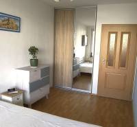 Na dlhodobý prenájom 2-izbový byt - kompletne zariadený, klimatizovaný - Spálňa v 2-izbovom byte s podlahou s dreveným dekorom, vstavanou skriňou a komodou.