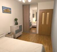 Na dlhodobý prenájom 2-izbový byt - kompletne zariadený, klimatizovaný - Spálňa v 2-izbovom byte s podlahou s dreveným dekorom, skrine so zrkadlom a obrazom.