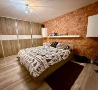 Dvojizbový byt, Považská Bystrica - Stred - Spálňa v 2-izbovom byte s posteľou, úložným priestorom a podlahou s dreveným dekorom.