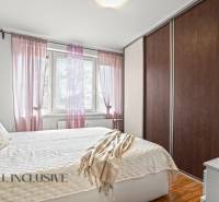 NA PREDAJ 3-IZBOVÝ BYT S PIVNICOU, SENEC - Spálňa v 3-izbovom byte s posteľou, skriňou a dekoratívnymi vankúšmi, podlaha s dreveným dekorom.