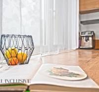 NA PREDAJ 3-IZBOVÝ BYT S PIVNICOU, SENEC - Otvorená kuchyňa v 3-izbovom byte s dreveným dekorom, miska s ovocím na stole.