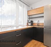 NA PREDAJ 3-IZBOVÝ BYT S PIVNICOU, SENEC - Kuchyňa v 3-izbovom byte s veľkým oknom, čiernymi skrinkami a podlahou s dreveným dekorom.