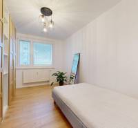 Kvalitne rekonštruovaný byt vo výbornej lokalite Petržalky - Spálňa s podlahou s dreveným dekorom, posteľou a skriňou v 3-izbovom byte.