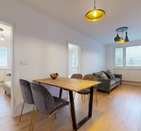 Kvalitne rekonštruovaný byt vo výbornej lokalite Petržalky - Interiér 3-izbového bytu s podlahou s dreveným dekorom, jedálenským stolom a pohovkou.