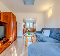 2 IZBOVÝ BYT PREŠOV, ULICA TARASA ŠEVČENKA - Obývacia izba v 2-izbovom byte s podlahou s dreveným dekorom a presvetlenou kuchyňou.