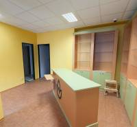 NA PRENÁJOM KOMERČNÝ PRIESTOR (80m2) V CENTRE SENICE - Žlté steny, pult, regály a dlaždice v obchodných priestoroch s podlahou s dreveným dekorom.