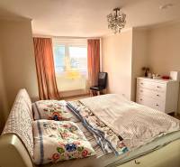 EXKLUZÍVNE - Veľký 3i byt s benefitmi rodinného domu, Boleráz - Spálňa v 3-izbovom byte s posteľou, skriňou a oknom s oranžovými závesmi.