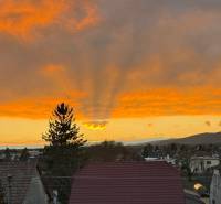 EXKLUZÍVNE - Veľký 3i byt s benefitmi rodinného domu, Boleráz - Boleráz pri západe slnka, vidno strechy domov a dramatickú oblohu.