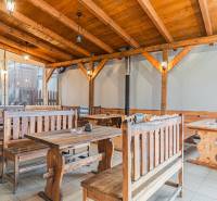 Predaj Exkluzívna ponuka elegantného penziónu s hostincom - Drevený interiér reštaurácie s lavicami a stolmi v hotelovom a penziónovom štýle.