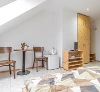 Predaj Exkluzívna ponuka elegantného penziónu s hostincom - Izba v Hotely a penzióny s dvojicou stoličiek, stolom, skriňou a posteľou.