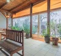 Predaj Exkluzívna ponuka elegantného penziónu s hostincom - Slnečný priestor s dreveným sedením v Hoteloch a penziónoch, obklopený rastlinami.