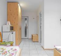 Predaj Exkluzívna ponuka elegantného penziónu s hostincom - Interiér penziónu s posteľami, televízorom, skriňou, mikrovlnkou a chladničkou.