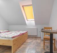 Predaj Exkluzívna ponuka elegantného penziónu s hostincom - Izba v Hoteloch a penziónoch s dreveným stolom, kvetinovými obliečkami a šikmým oknom.