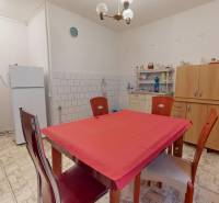 NA PREDAJ 5 IZBOVÝ POSCHODOVÝ DOM V CENTRE OBCE, IŽA, OKRES KOMÁRNO - Kuchyňa v rodinnom dome s bielou chladničkou, mikrovlnkou a jedálenským stolom.