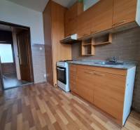 REZERVOVANÉ 2-izbový byt s nádherným výhľadom v pôvodnom stave   - Kuchyňa s kuchynskou linkou a spotrebičmi v 2-izbovom byte na podlahe s dreveným dekorom.
