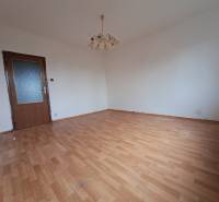 REZERVOVANÉ 2-izbový byt s nádherným výhľadom v pôvodnom stave   - Izba v 2-izbovom byte s bielymi stenami a podlahou s dreveným dekorom.