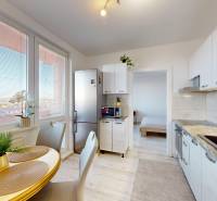 ZREKONŠTRUOVANÝ 3-IZBOVÝ BYT (74 m2) S BALKÓNOM, PIVNICOU, 2 x WC - Kuchyňa v 3-izbovom byte s jedálenským stolom, podlahou s dreveným dekorom a veľkými oknami.